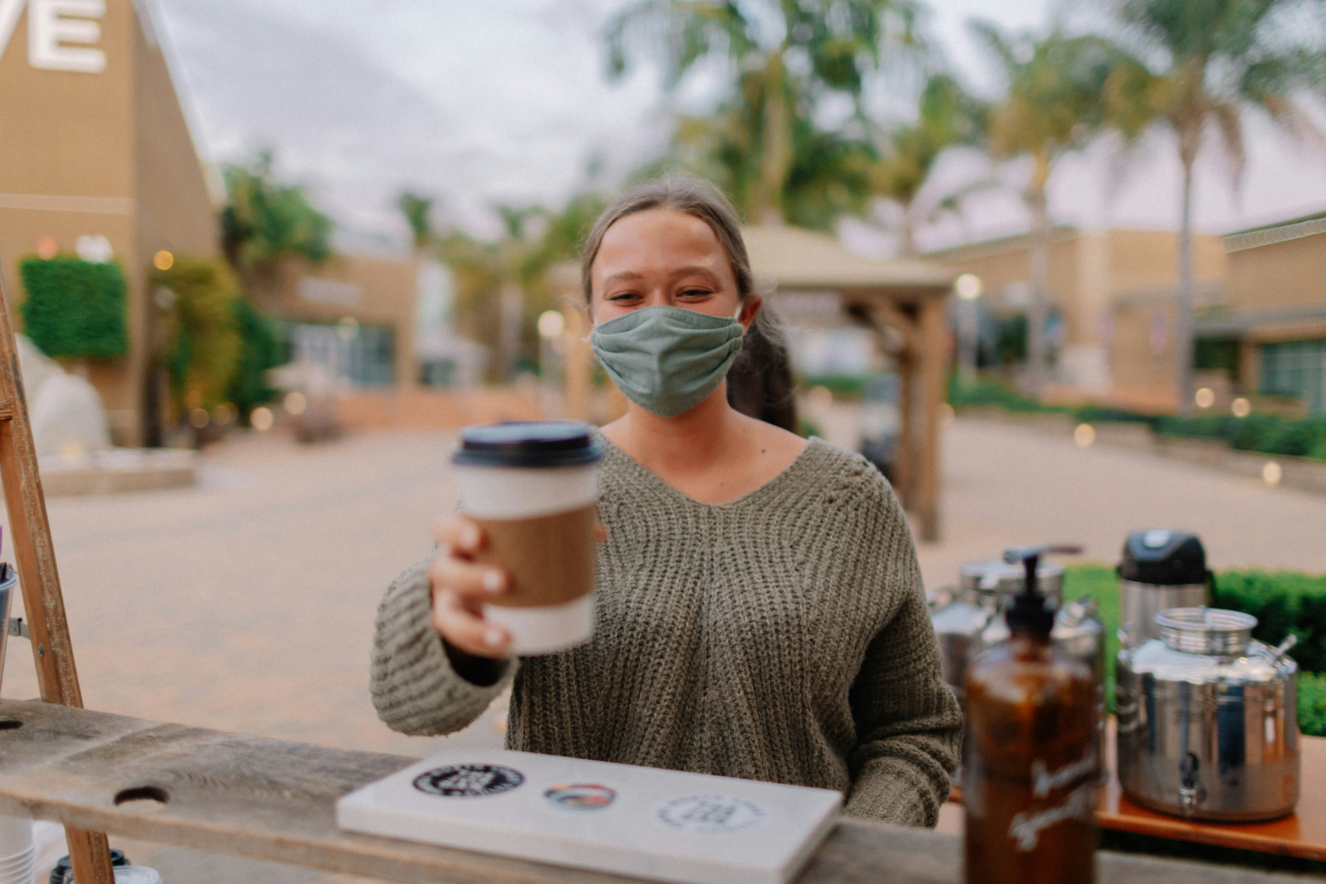 woman in gray sweater drinking from white and blue cup